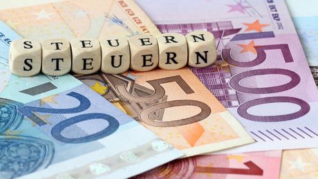 Geldscheine und Würfel mit der Aufschrift Steuer