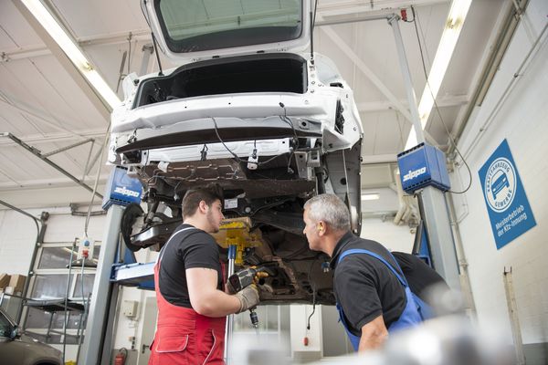 Kfz Mechatroniker bei der Arbeit ind er Werkstat unter der Hebebühne