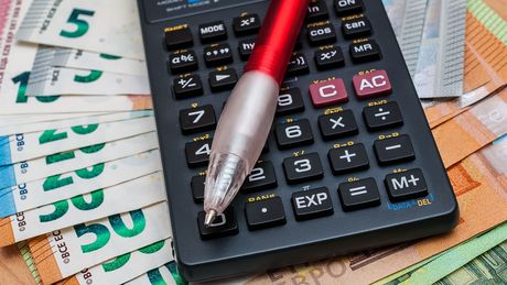 Taschenrechner, Geldscheine und Stift auf einem Tisch